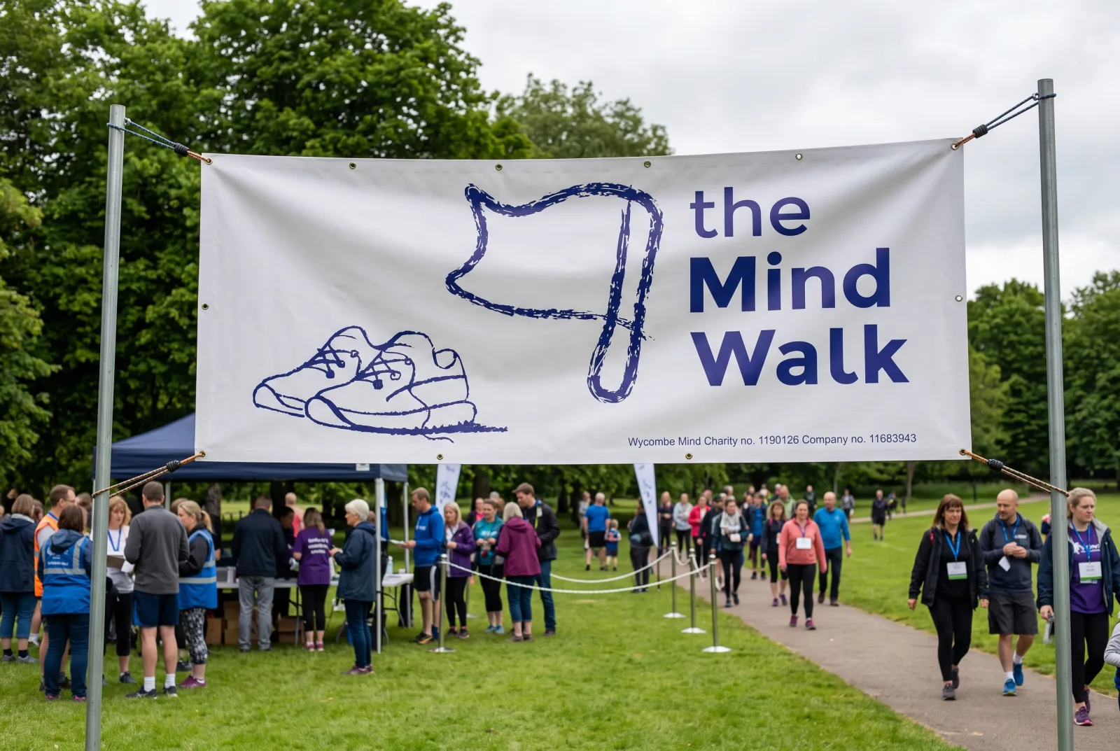 Custom printed banner for a charity walk event: a large white banner with a navy logo design hung above a park gathering