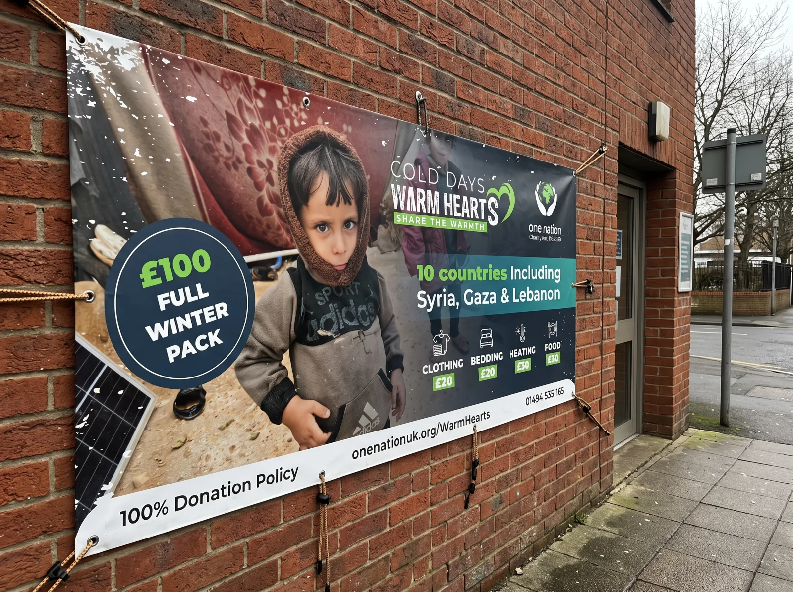 Large printed outdoor banner with eyelets and ties fixed to a brick building wall