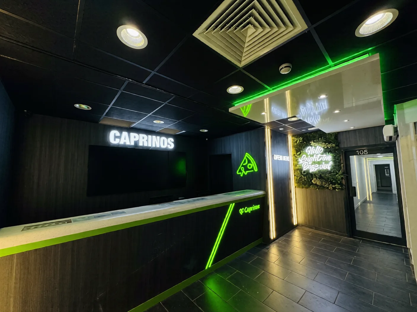 Takeaway branding with a lit 3D name sign, green LED pizza logo and illuminated counter in a black shop interior